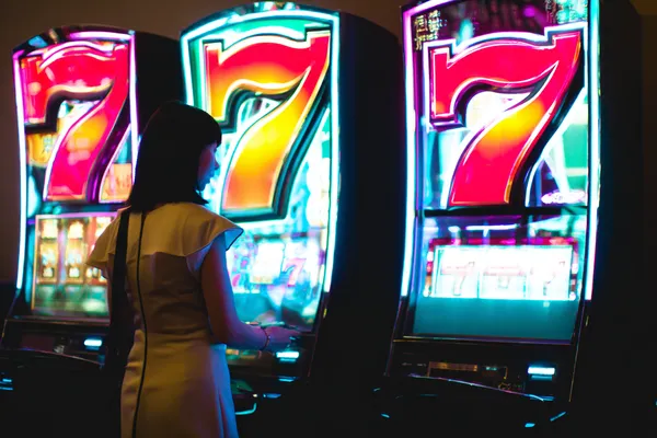 A woman smiling while playing online games on her laptop, surrounded by neon casino elements, showcasing ZEUS75’s diverse game collection.